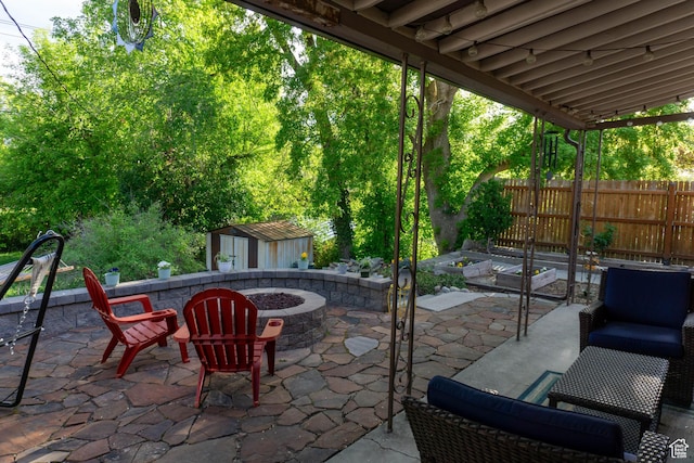 view of patio with a fire pit, a storage shed, an outdoor structure, and fence