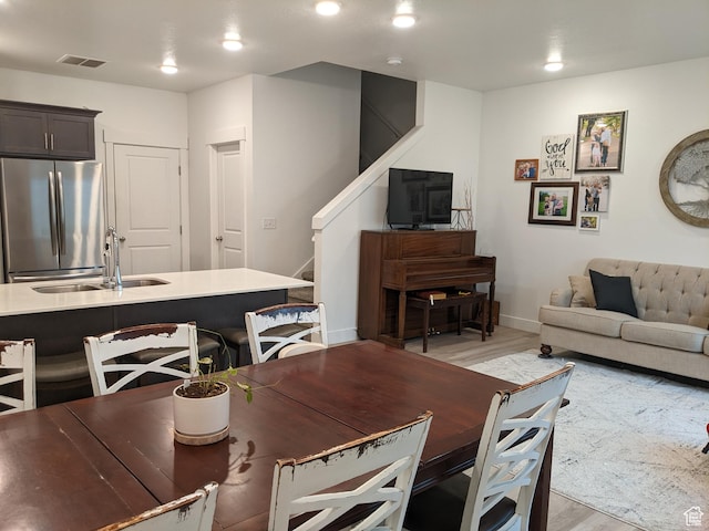 dining room featuring light wood-type flooring, stairs, and baseboards