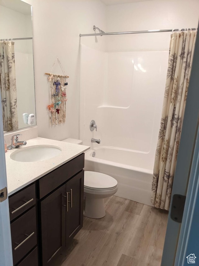 bathroom with wood finished floors, toilet, shower / bath combo, and vanity