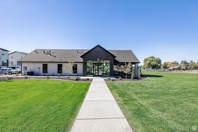 modern farmhouse with a front yard, a shingled roof, and central AC unit