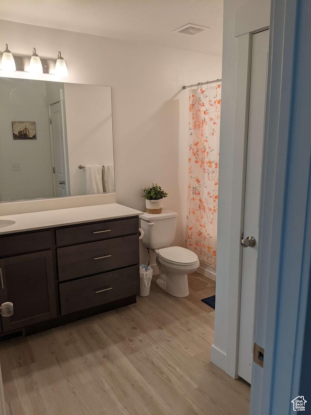 full bathroom with wood finished floors, vanity, toilet, and curtained shower