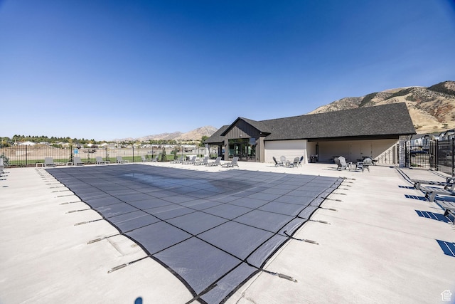 view of swimming pool featuring a mountain view, fence, and a patio area
