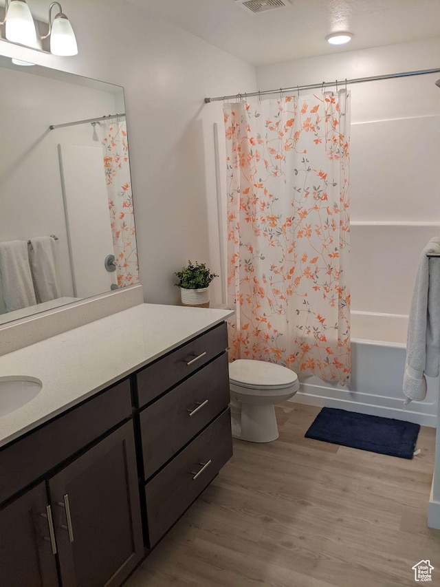 full bathroom featuring wood finished floors, vanity, toilet, and shower / tub combo with curtain