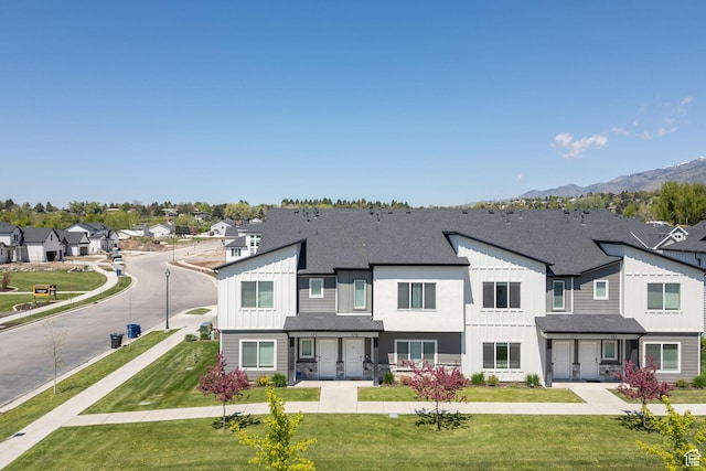 view of front of home featuring board and batten siding, a residential view, a shingled roof, and a mountain view