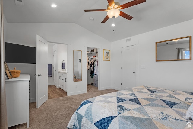 bedroom with light carpet, a spacious closet, vaulted ceiling, ensuite bath, and ceiling fan