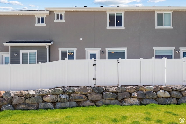 back of house featuring fence and stucco siding