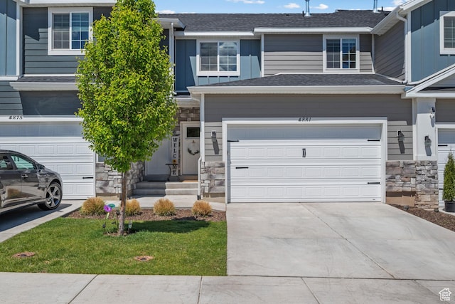 multi unit property with stone siding, concrete driveway, roof with shingles, and a garage