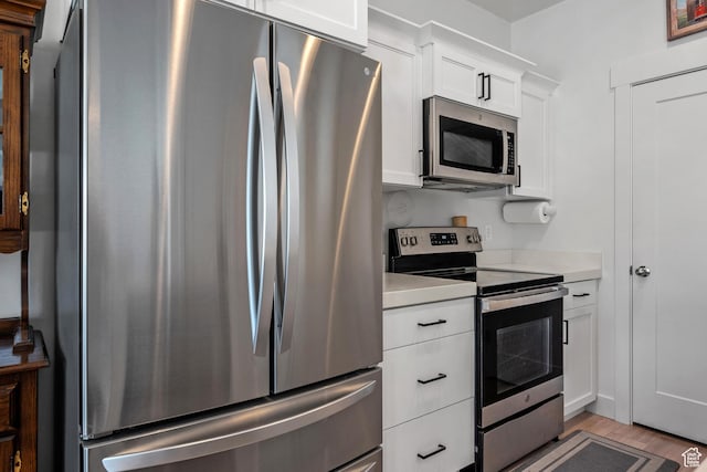 kitchen featuring appliances with stainless steel finishes, light countertops, white cabinetry, and light wood-type flooring