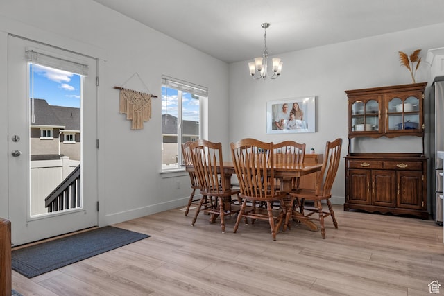 dining room featuring a chandelier, light wood-style floors, and baseboards