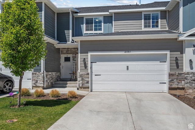 view of front facade featuring stone siding, a garage, and driveway