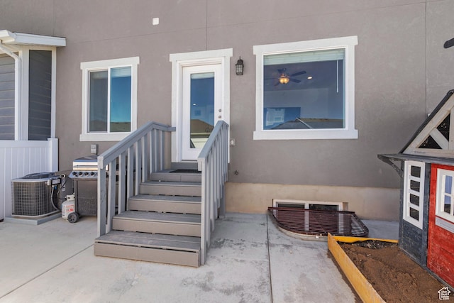 view of exterior entry with stucco siding and central AC unit