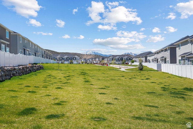 view of yard featuring a residential view, fence, and a mountain view