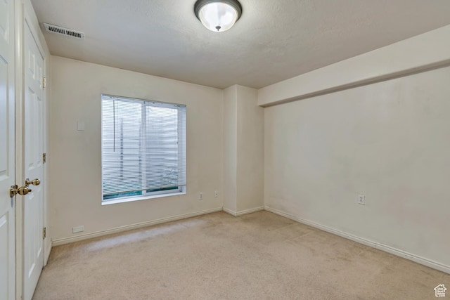 spare room with light colored carpet and baseboards
