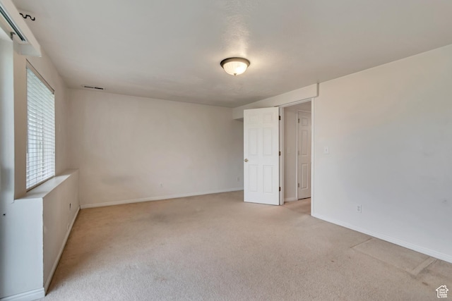 spare room with light carpet and baseboards