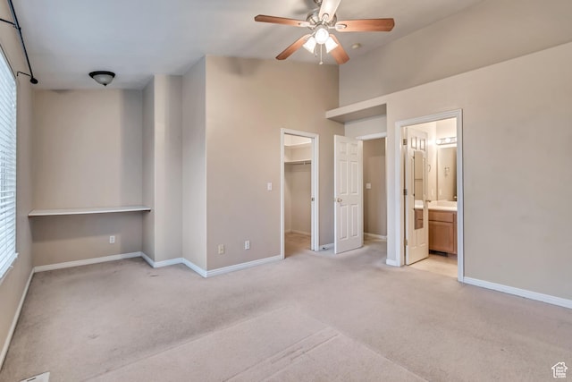 unfurnished bedroom with light colored carpet, a walk in closet, and baseboards