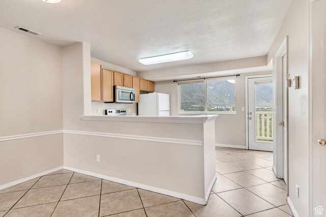 768 E 1740 S Unit 768, Orem, UT 84097 - kitchen with stainless steel microwave, freestanding refrigerator, light tile patterned floors, light brown cabinets, and stove