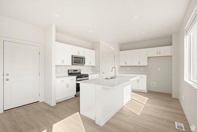 3523 N Browning St Unit 1233, Eagle Mountain, UT 84005 - kitchen with stainless steel appliances, a center island with sink, light wood-type flooring, white cabinetry, and light countertops