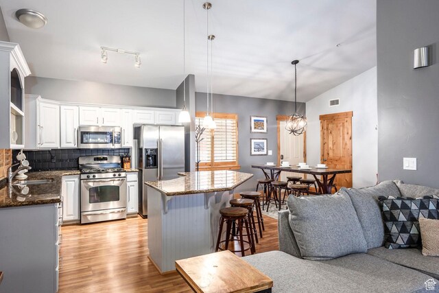 5501 Lillehammer Ln Unit 4306, Park City, UT 84098 - kitchen with stainless steel appliances, a sink, light wood-style flooring, a kitchen bar, and white cabinetry