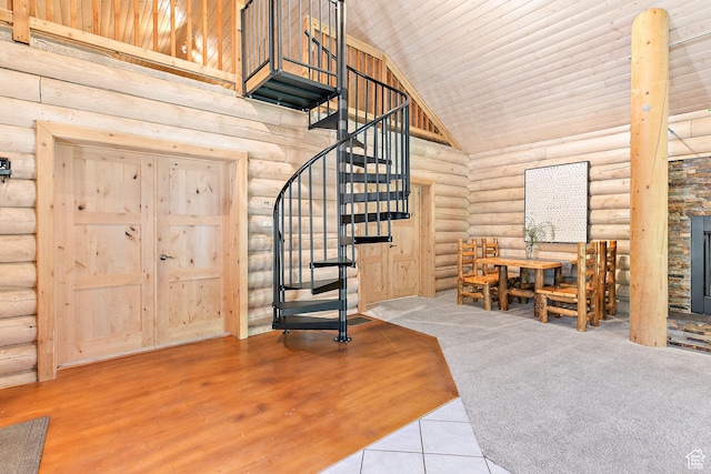 entrance foyer featuring log walls, a towering ceiling, stairs, tile patterned flooring, and a fireplace