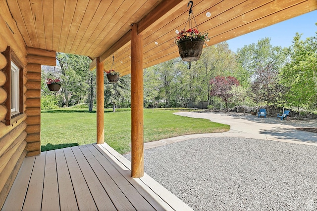 wooden deck featuring a lawn, a patio area, and view of wooded area
