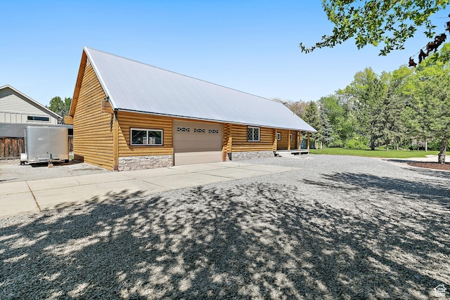 view of property exterior with stone siding, metal roof, concrete driveway, and an attached garage
