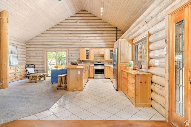 kitchen with appliances with stainless steel finishes, rustic walls, light brown cabinets, high vaulted ceiling, and a breakfast bar area