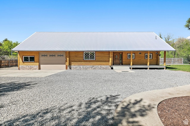 cabin featuring fence, a garage, concrete driveway, log siding, and metal roof