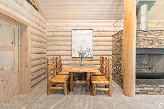 carpeted dining space featuring log walls, a stone fireplace, and wooden ceiling
