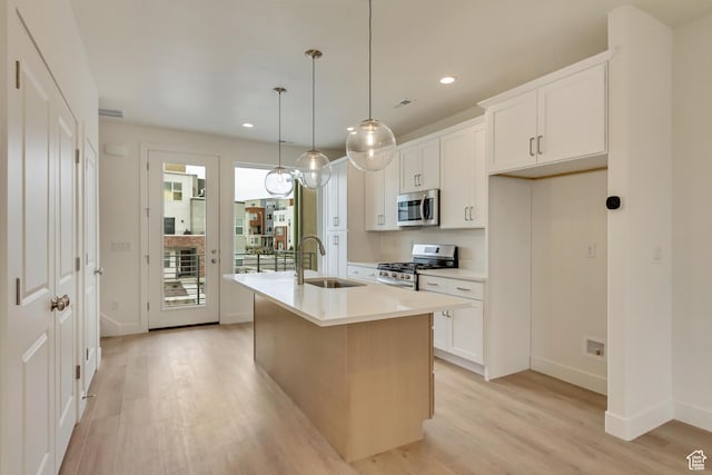 kitchen featuring stainless steel appliances, a sink, light wood-style floors, baseboards, and recessed lighting