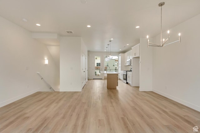 unfurnished living room with light wood finished floors, recessed lighting, a chandelier, baseboards, and a sink