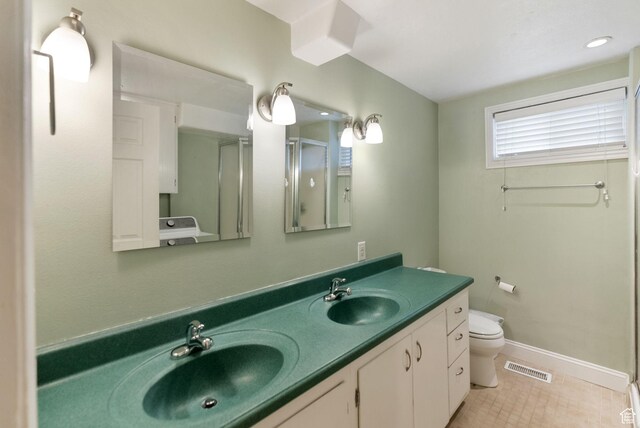 full bath featuring toilet, double vanity, a shower stall, baseboards, and tile patterned floors