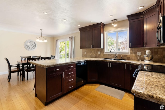 kitchen with black appliances, a sink, light wood-type flooring, a peninsula, and tasteful backsplash