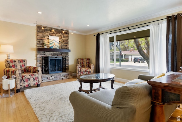 living area featuring crown molding, a fireplace, wood finished floors, and baseboards