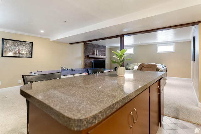kitchen with light carpet, open floor plan, a kitchen island, baseboards, and a brick fireplace