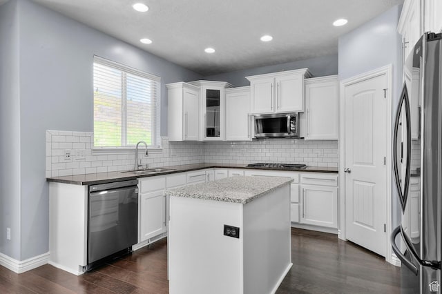 kitchen with appliances with stainless steel finishes, a sink, dark wood-style flooring, white cabinetry, and recessed lighting