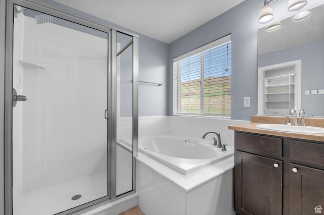 bathroom with a shower stall, a bath, and vanity