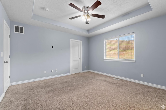 carpeted spare room featuring a tray ceiling, a textured ceiling, ceiling fan, baseboards, and a smoke detector