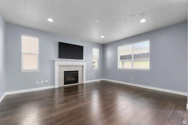 unfurnished living room with a textured ceiling, recessed lighting, baseboards, a fireplace, and wood finished floors