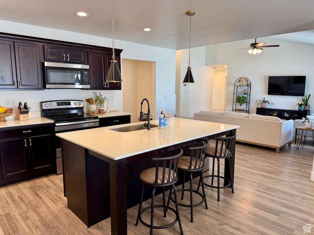 167 E Craner Peak Dr, Eagle Mountain, UT 84005 - kitchen with appliances with stainless steel finishes, a sink, light wood finished floors, a kitchen bar, and recessed lighting