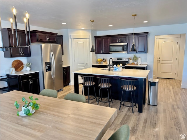 167 E Craner Peak Dr, Eagle Mountain, UT 84005 - kitchen with stainless steel appliances, a sink, light countertops, light wood-style flooring, and a breakfast bar area