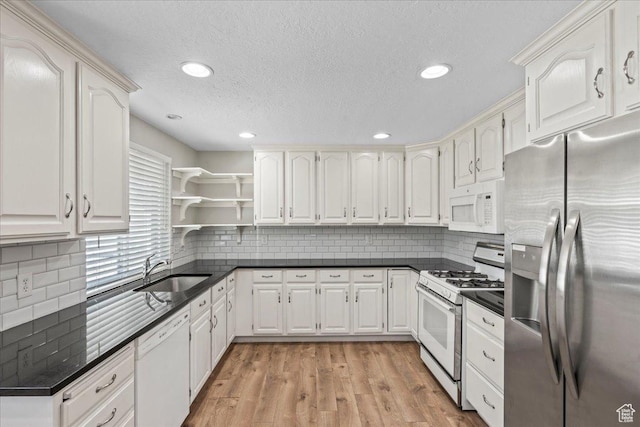 kitchen featuring white appliances, a sink, dark countertops, open shelves, and recessed lighting