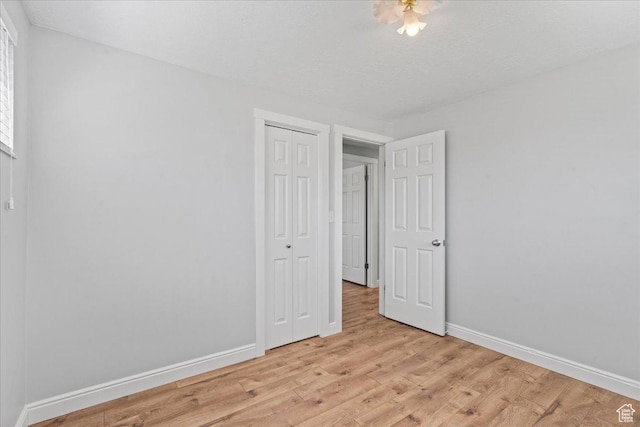 unfurnished bedroom with baseboards, a closet, and light wood-style flooring