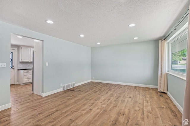 unfurnished room featuring light wood-type flooring, recessed lighting, a textured ceiling, and baseboards