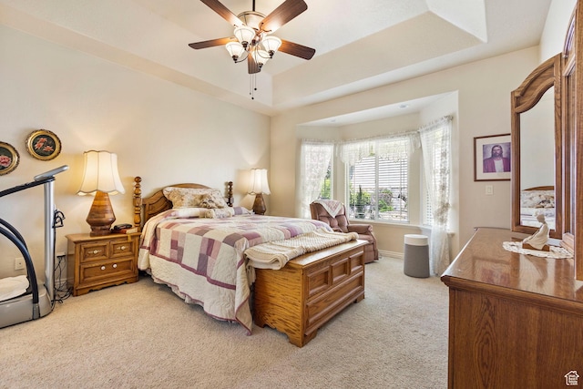 bedroom with light carpet, a tray ceiling, ceiling fan, and baseboards