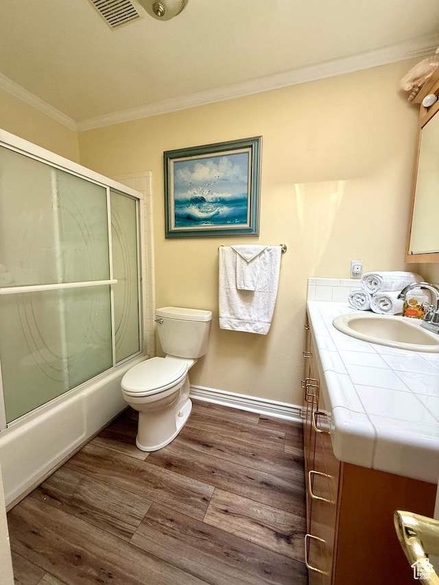 full bathroom with crown molding, vanity, wood finished floors, toilet, and shower / bath combination with glass door