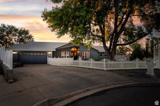 view of front of home with a fenced front yard, driveway, a garage, and a shingled roof