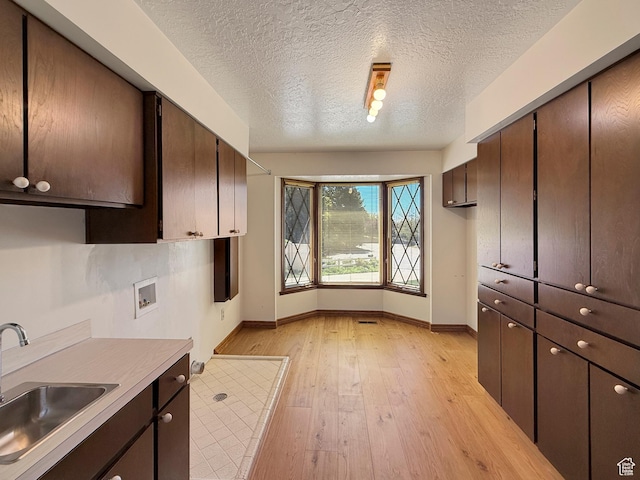 1145 E 1675 N, North Ogden, UT 84404 - kitchen featuring a sink, baseboards, light wood-style floors, dark brown cabinetry, and a textured ceiling