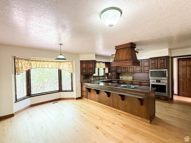 1145 E 1675 N, North Ogden, UT 84404 - kitchen featuring appliances with stainless steel finishes, island range hood, dark countertops, a kitchen breakfast bar, and baseboards