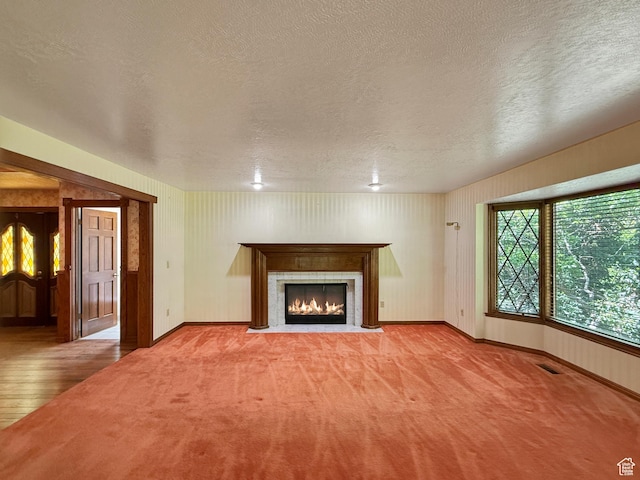 1145 E 1675 N, North Ogden, UT 84404 - unfurnished living room featuring a textured ceiling, a fireplace with flush hearth, baseboards, carpet flooring, and wood finished floors