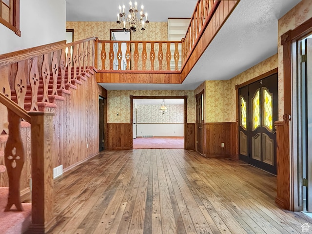 1145 E 1675 N, North Ogden, UT 84404 - unfurnished living room with wallpapered walls, a chandelier, a wainscoted wall, hardwood / wood-style floors, and stairs